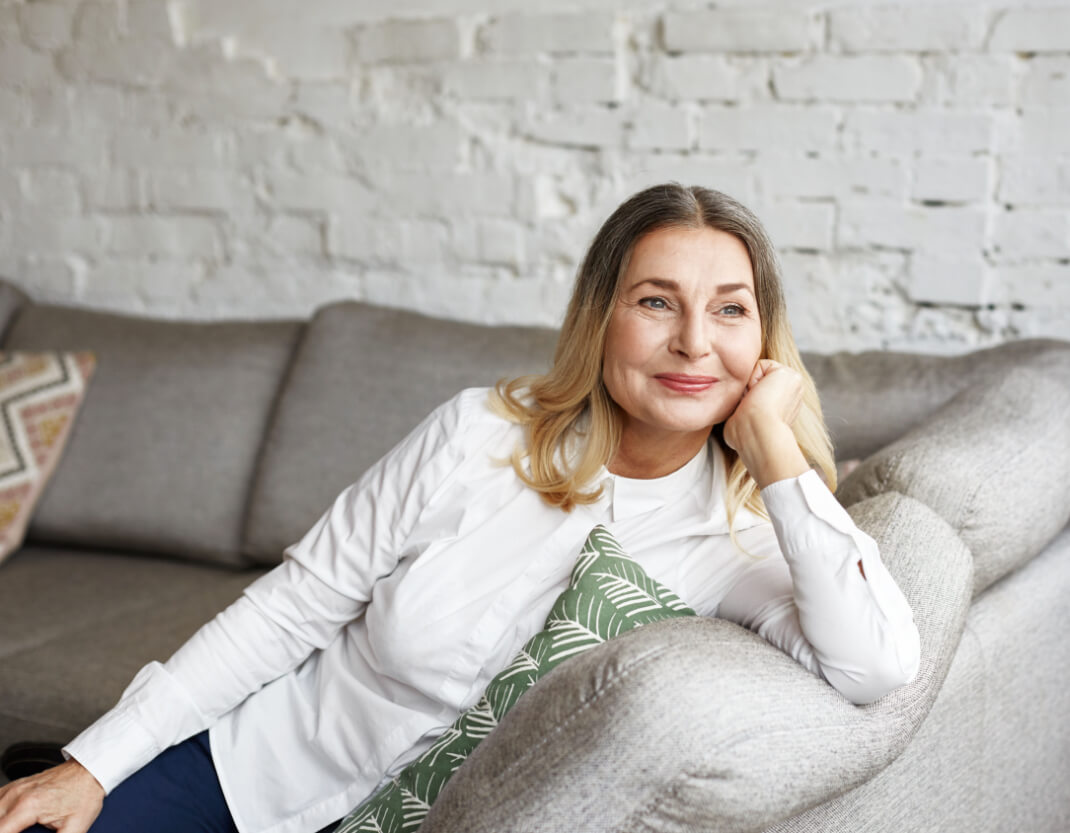 A happy lady sitting on her sofa.