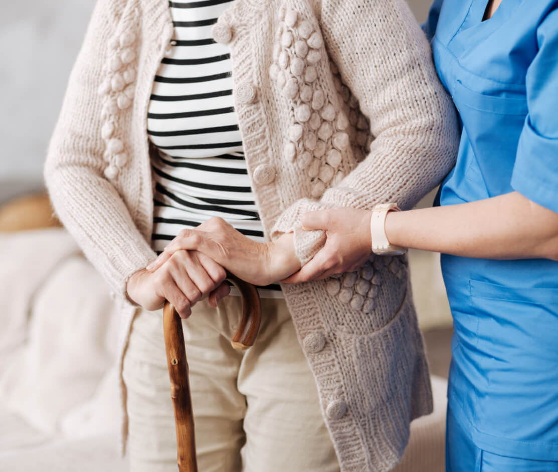 A nurse helping an older lady walk.